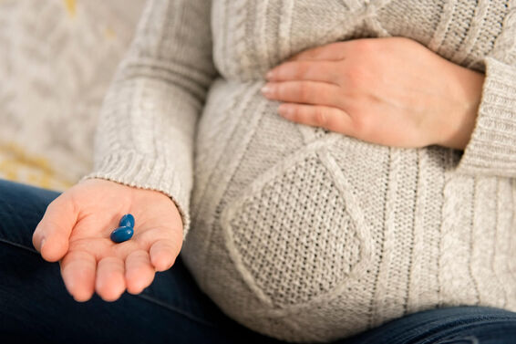 Pregnant woman holding pills in hand