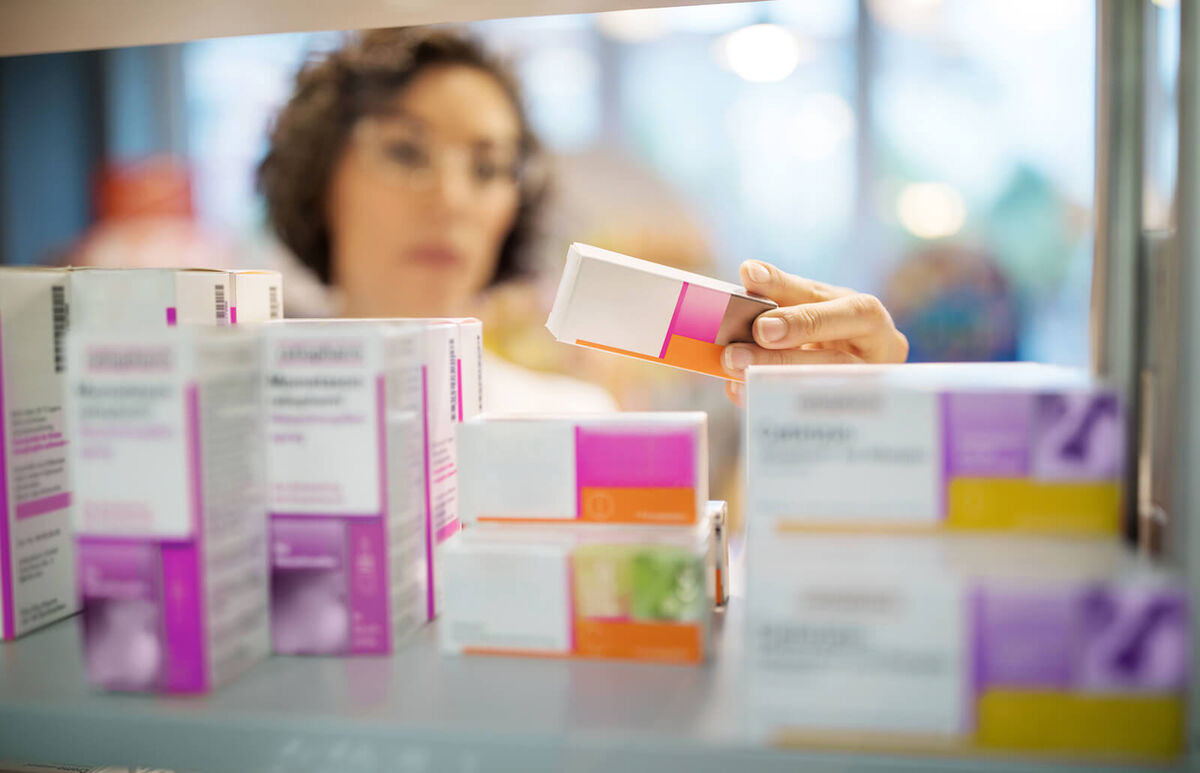 Female pharmacist checking medicines on rack