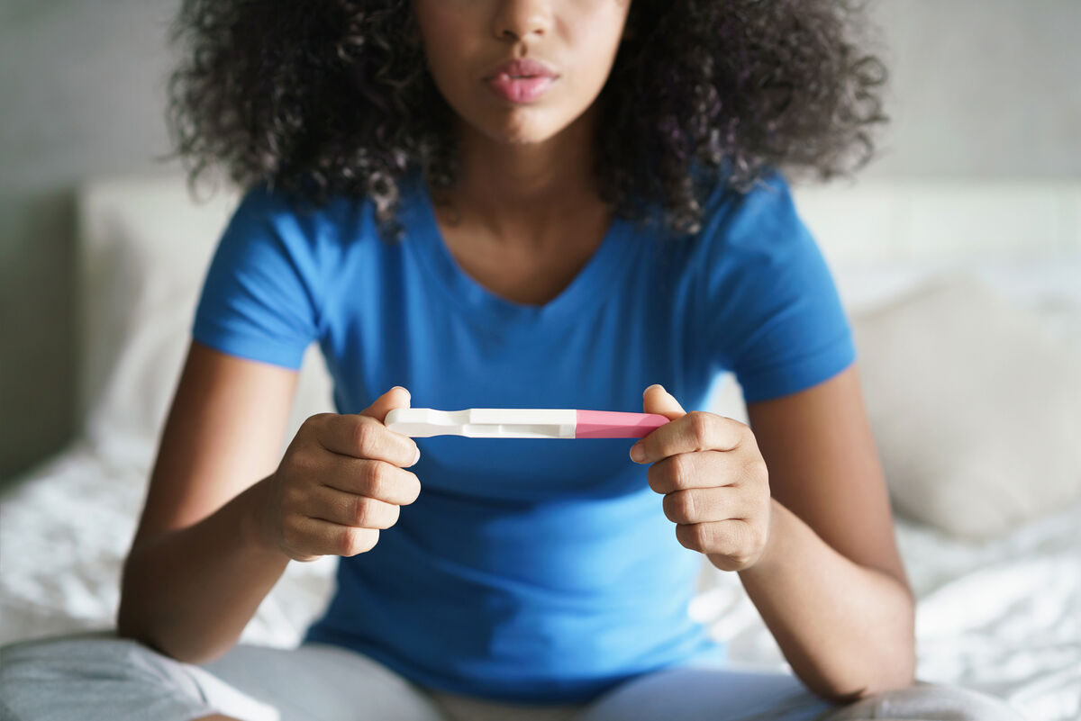 Sad Young Woman With Pregnancy Test At Home