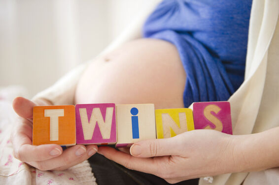 Pregnant woman holding wooden blocks saying "twins"