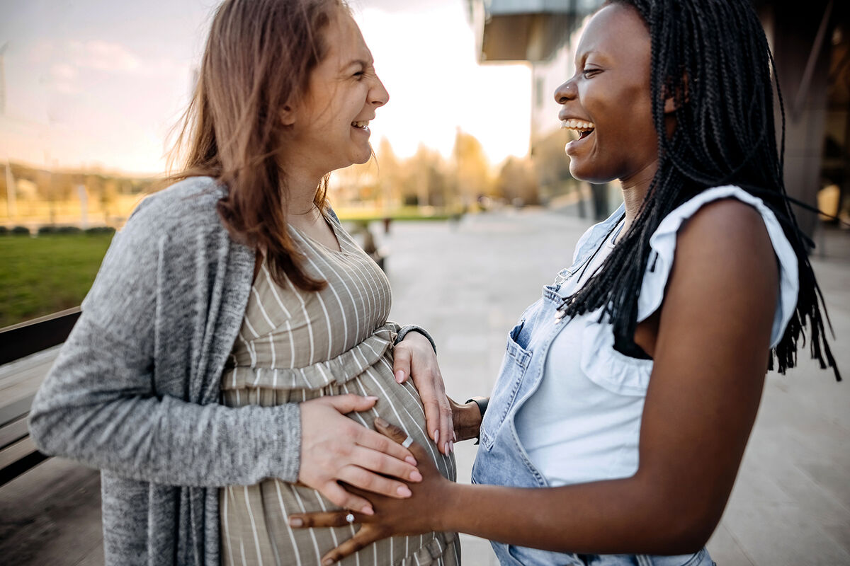 Best friend touching pregnant woman's belly
