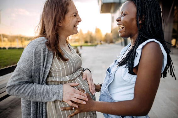 Best friend touching pregnant woman's belly