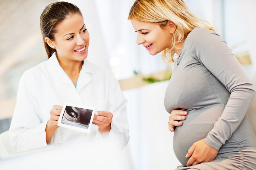 Technician showing a pregnant woman her ultrasound photo
