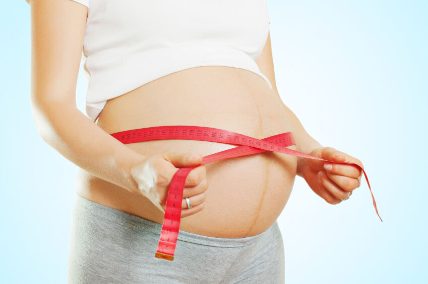 Pregnant woman measuring her belly at 32 weeks