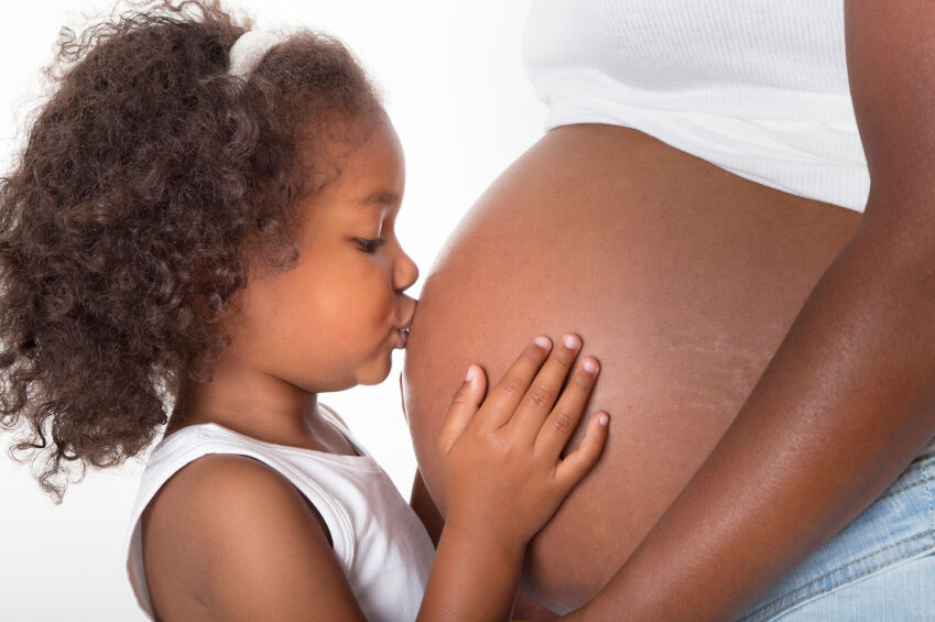 Little girl kissing pregnant mom's belly