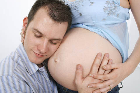 Husband listening to pregnant wife's belly