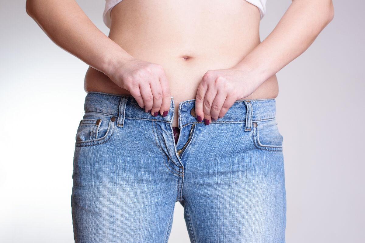 woman trying to button jeans