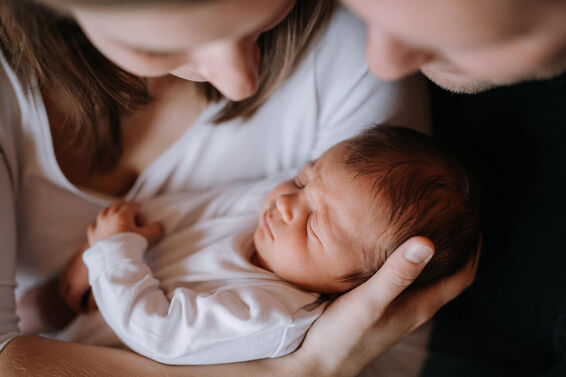 mother and father holding a newborn baby son at home