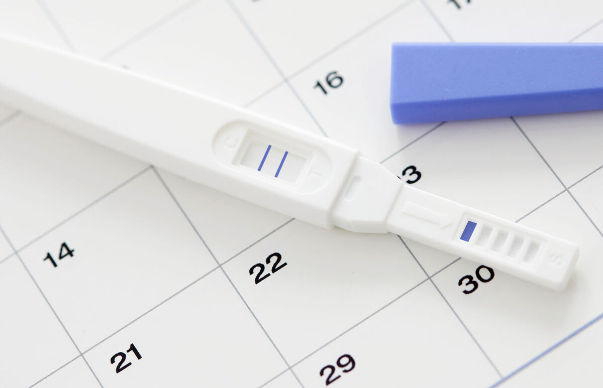 Pregnancy test showing positive result and calendar