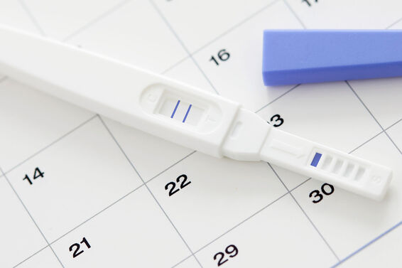Pregnancy test showing positive result and calendar