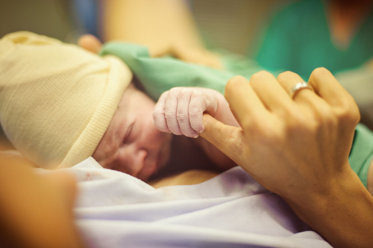 Image of newborn baby gripping mother's finger