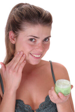 Young woman moisturizing her skin