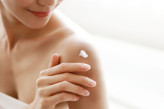 Woman applying body lotion on shoulder