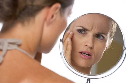 Woman looking at her face in the mirror