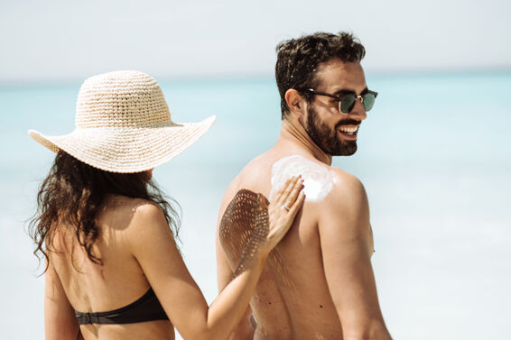 Woman applying sunscreen to man's back