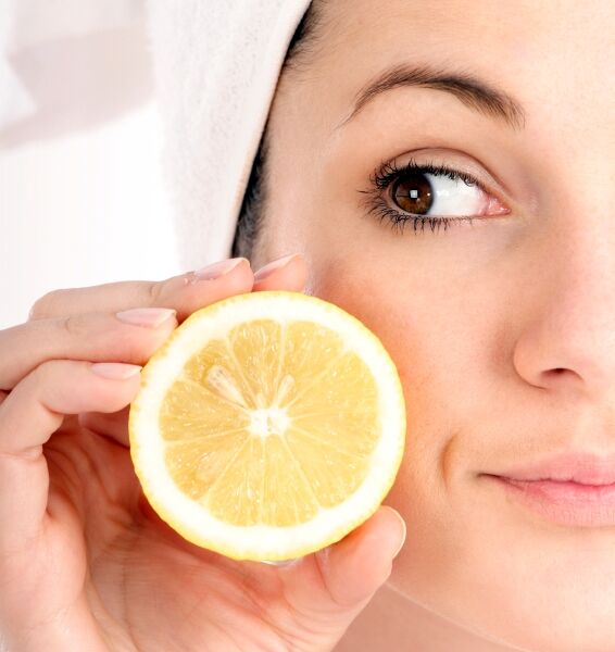 Woman holding a lemon slice near her face