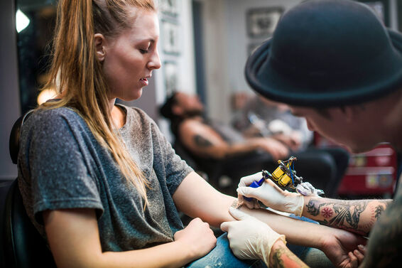 Artist making tattoo on woman's hand