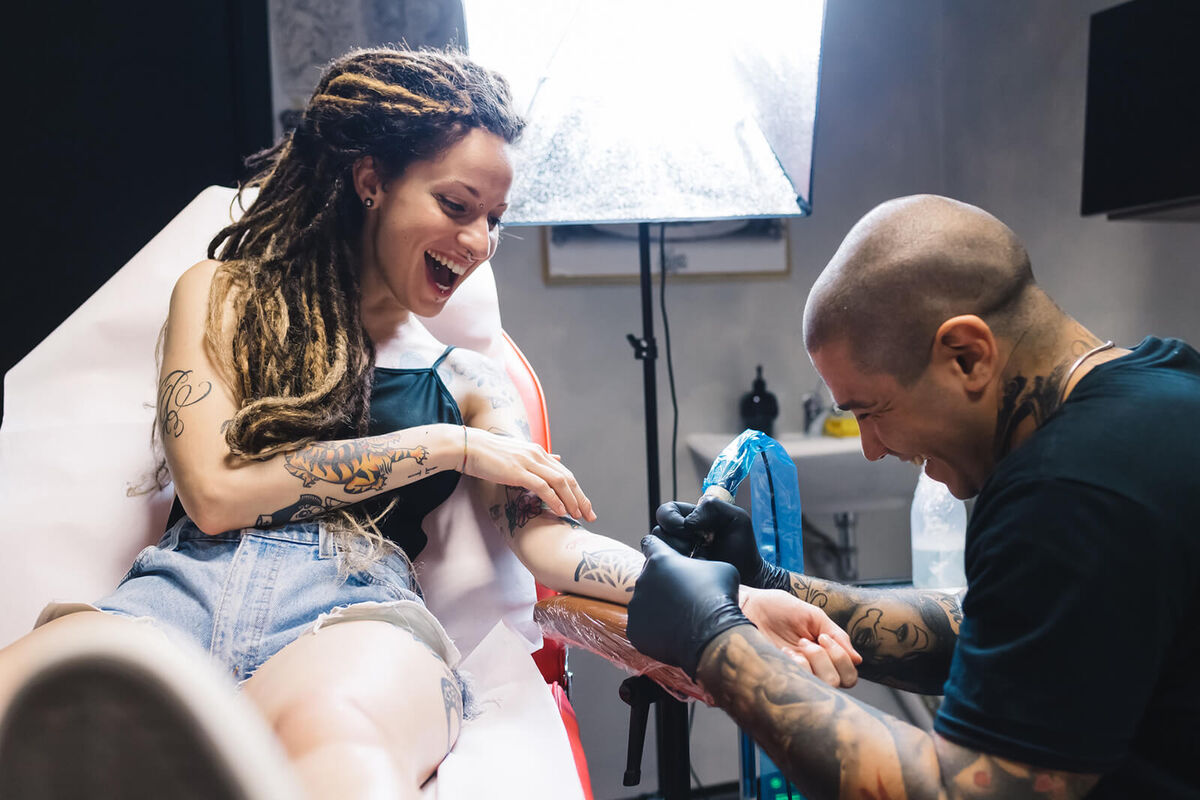 Tattooist drawing on arm of customer