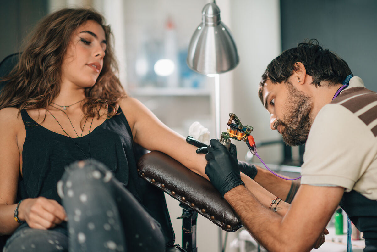 woman deep breathing to relax while getting a tattoo