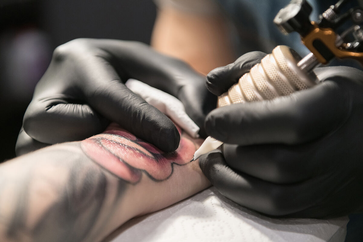 Cropped master drawing tattoo on arm
