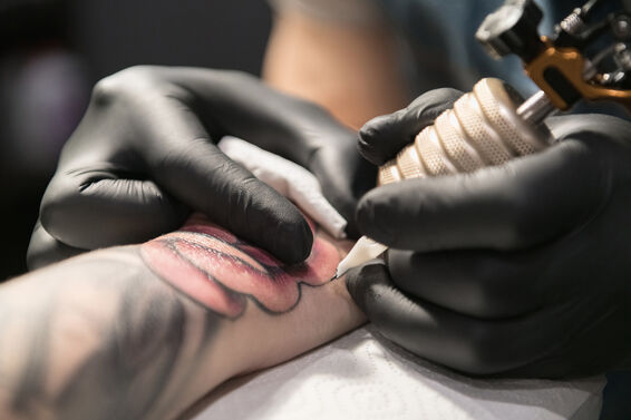 Cropped master drawing tattoo on arm
