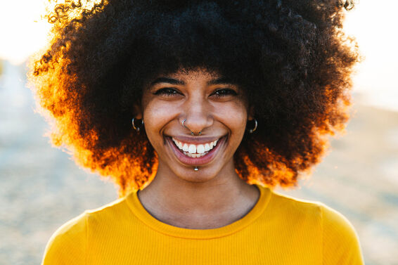 Smiling woman with Afro hairstyle at beach during sunset