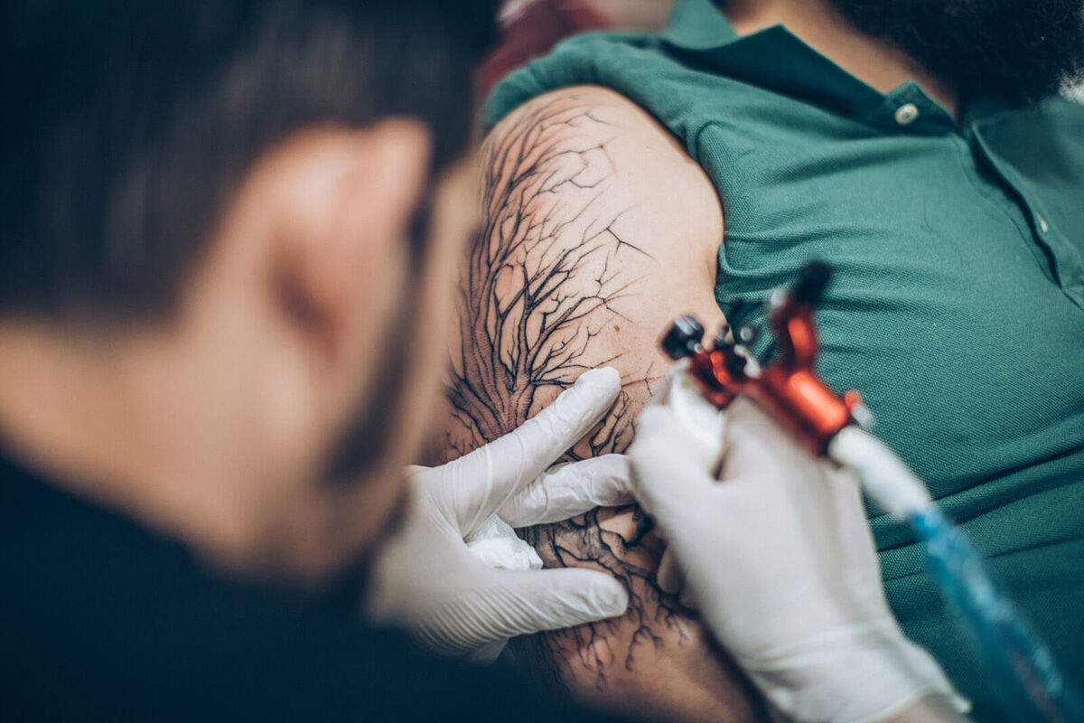Artist drawing tattoo on man's hand