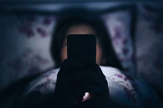 Woman reading and texting on smartphone in bed