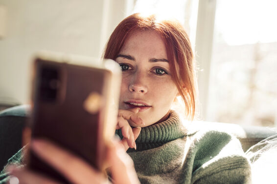 Woman with red hair looking on screen of her mobile phone