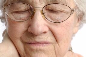 Elderly woman rubbing her painful neck