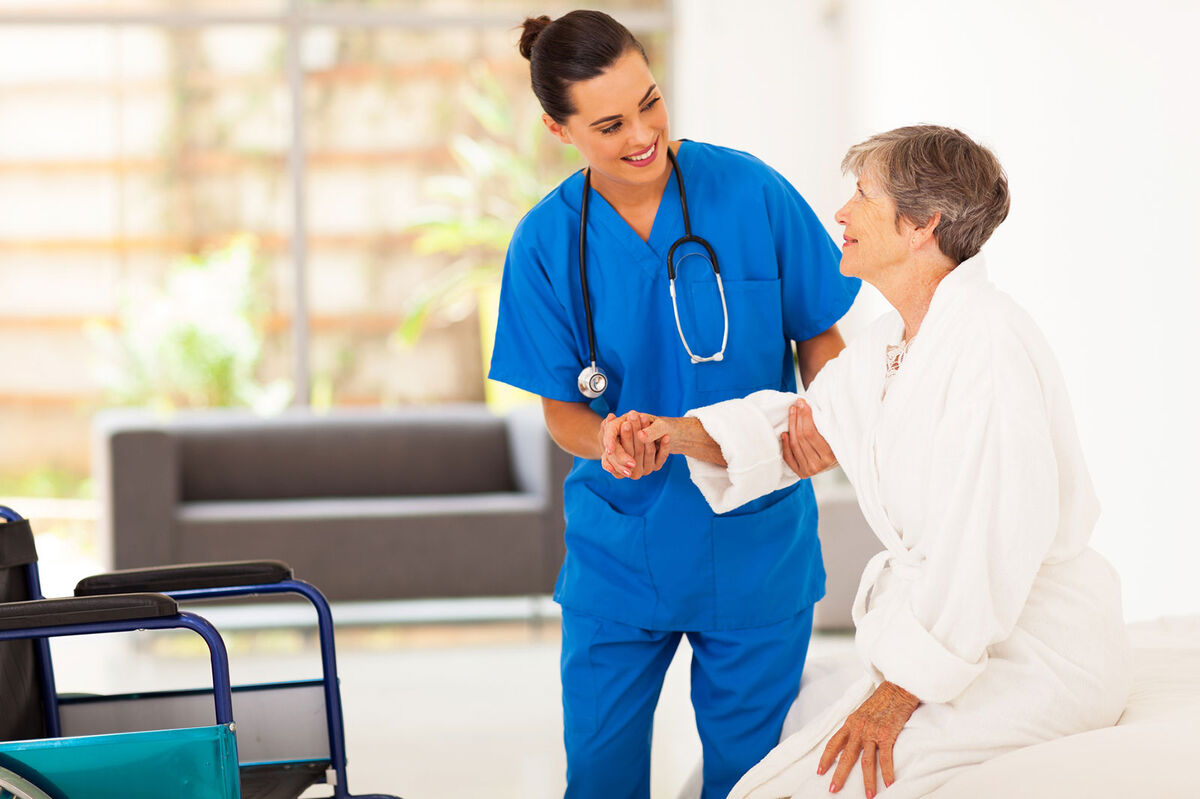 Nurse Helping Senior Woman into wheelchair