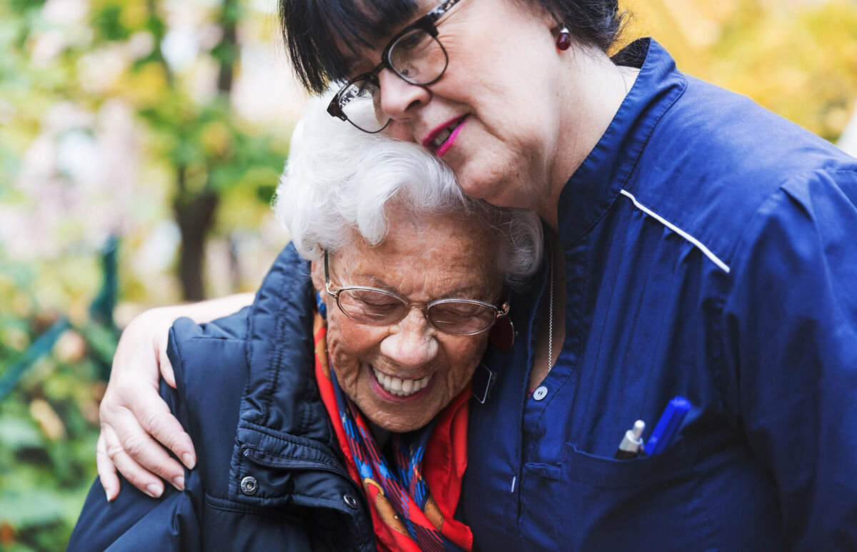 Caretaker embracing senior woman