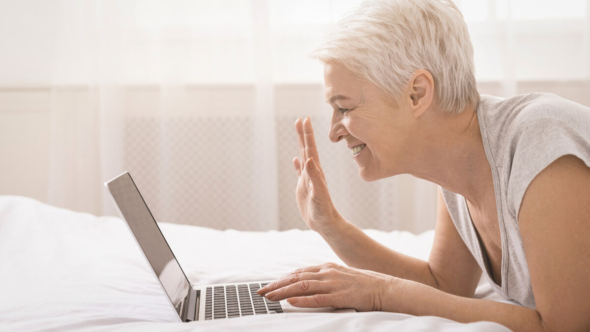 Cheerful grandmother talking with relatives via laptop onlin