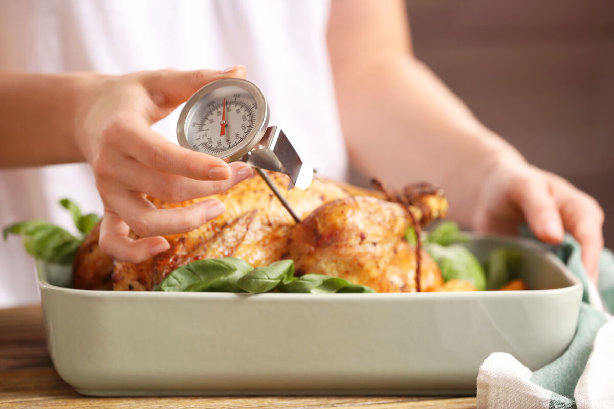 Using a food thermometer to check temperature of roast turkey