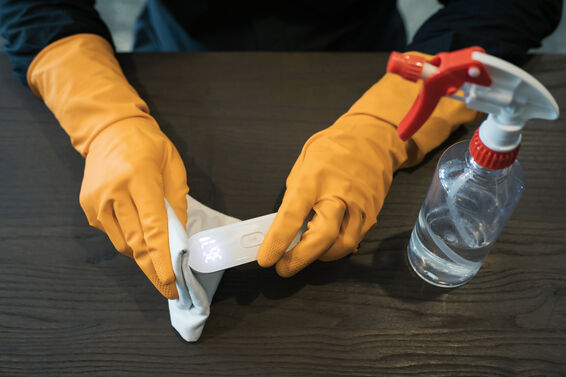 Hands with protective gloves disinfecting thermometer gun