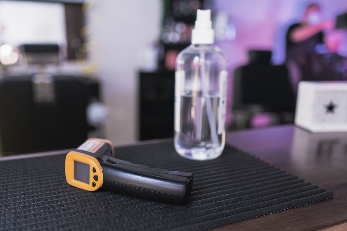 Hands with protective gloves disinfecting thermometer gun