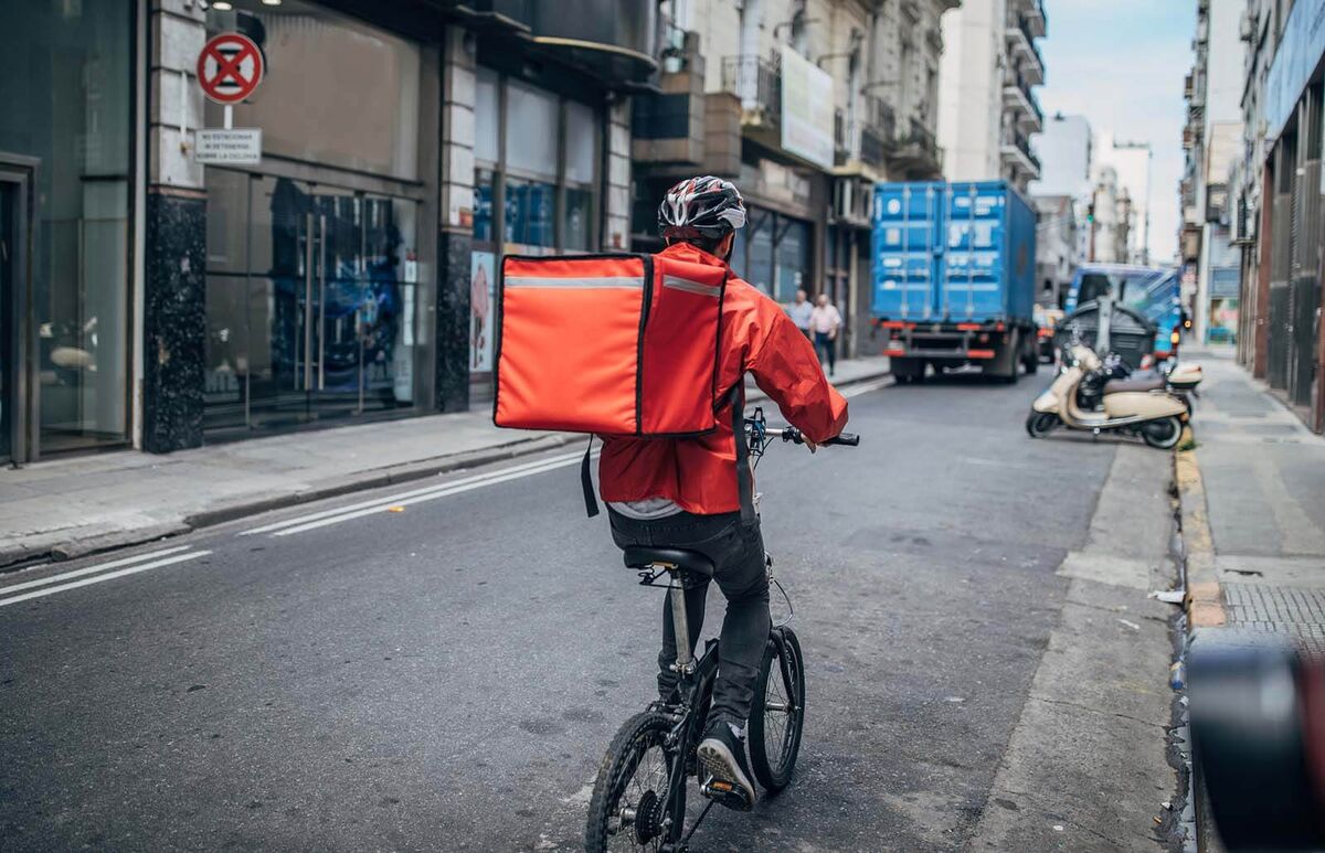 Delivery boy on bicycle in city