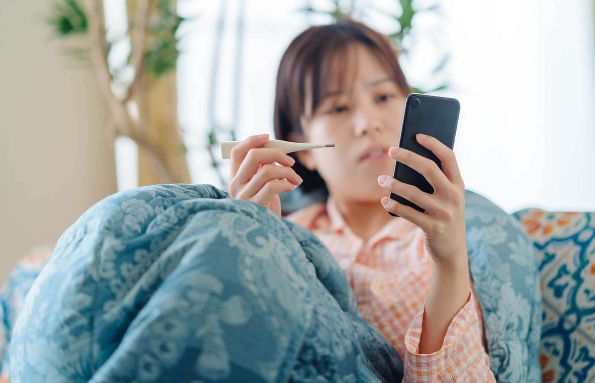 sick woman on phone taking temperature