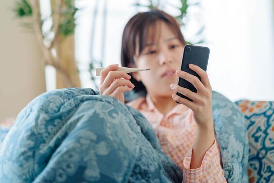 sick woman on phone taking temperature