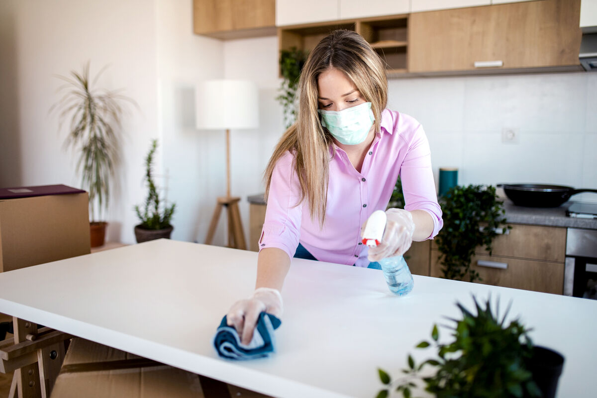 Young woman wearing mask for protection while cleaning