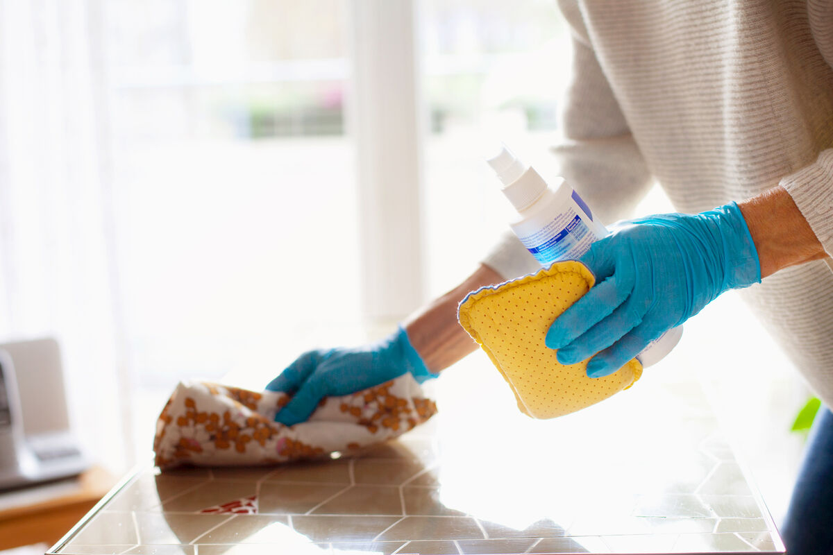 Woman cleaning table with disinfectant spray