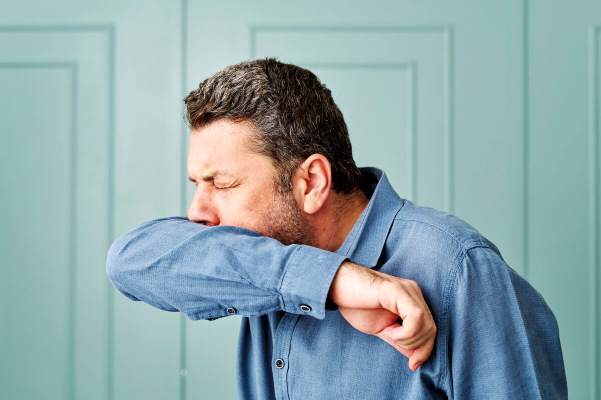 Man coughing at his elbow